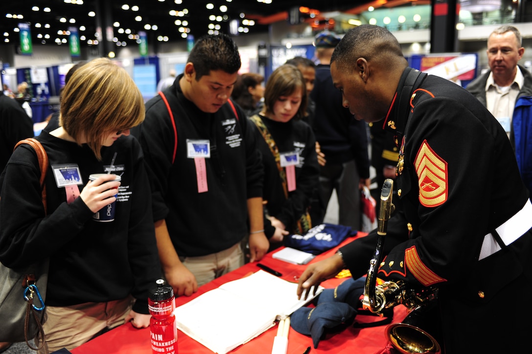Gunnery Sgt. Jason Knuckles, the musician technical assistant for the 9th Marine Corps District, speaks to a group of high school students at a Marine Corps Music Program booth, during the 2011 Midwest Clinic, Dec. 14. The Midwest Clinic is an annual event to promote music education.